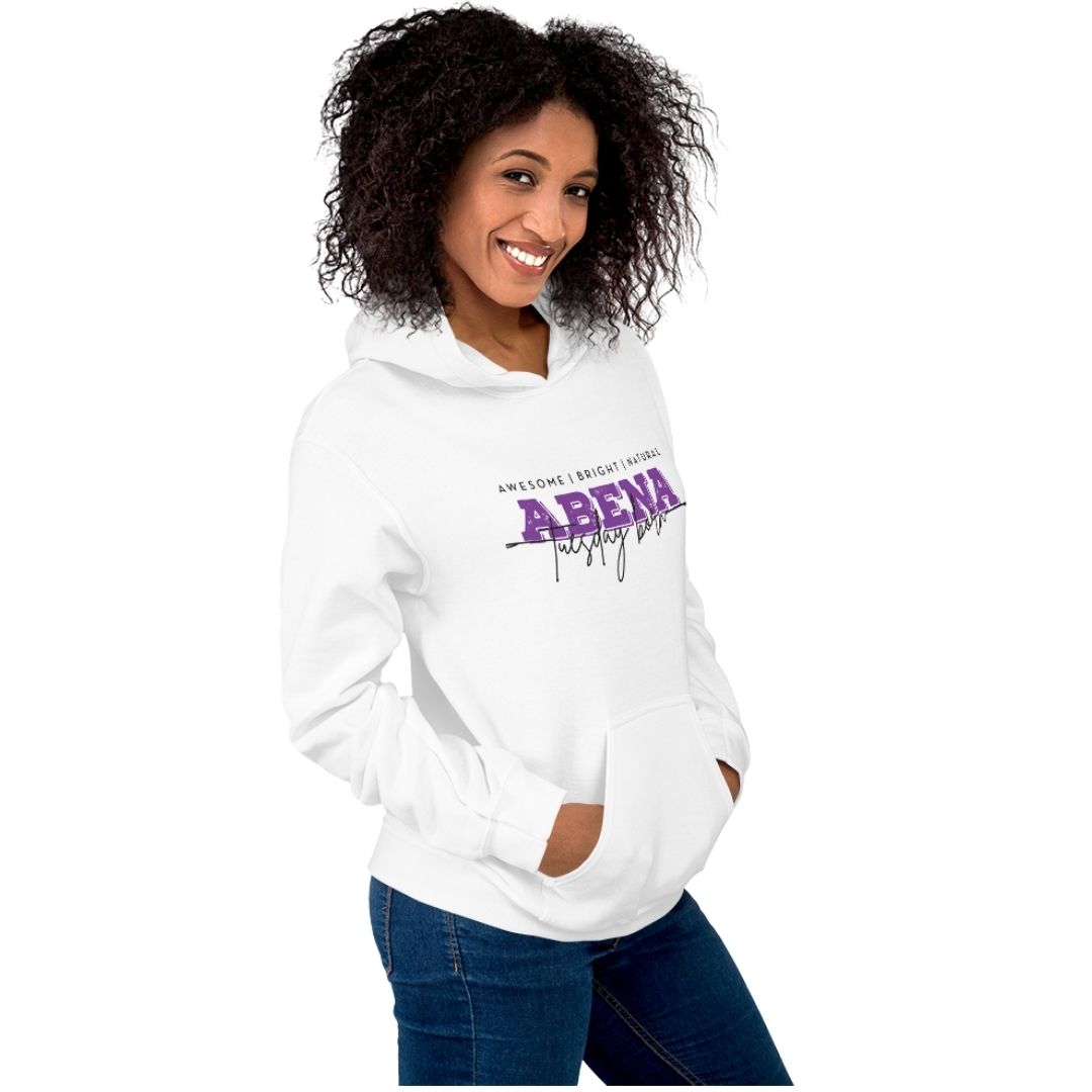 A woman with curly dark hair wearing a white pullover hoodie with a purple and black 'ARENA' graphic on the chest, paired with blue jeans, set against a plain white background.