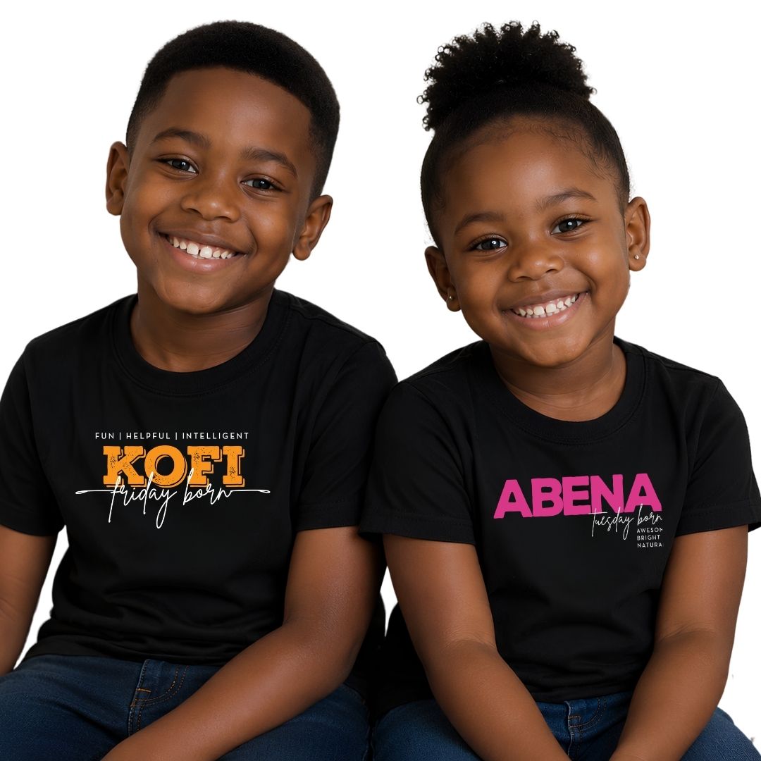Two young children, a boy and a girl, smiling and wearing matching black t-shirts with personalized names printed on the front. The boy's shirt is printed with 'KOFI' in orange and white, and the girl's shirt is printed with 'ABENA' in pink and white.