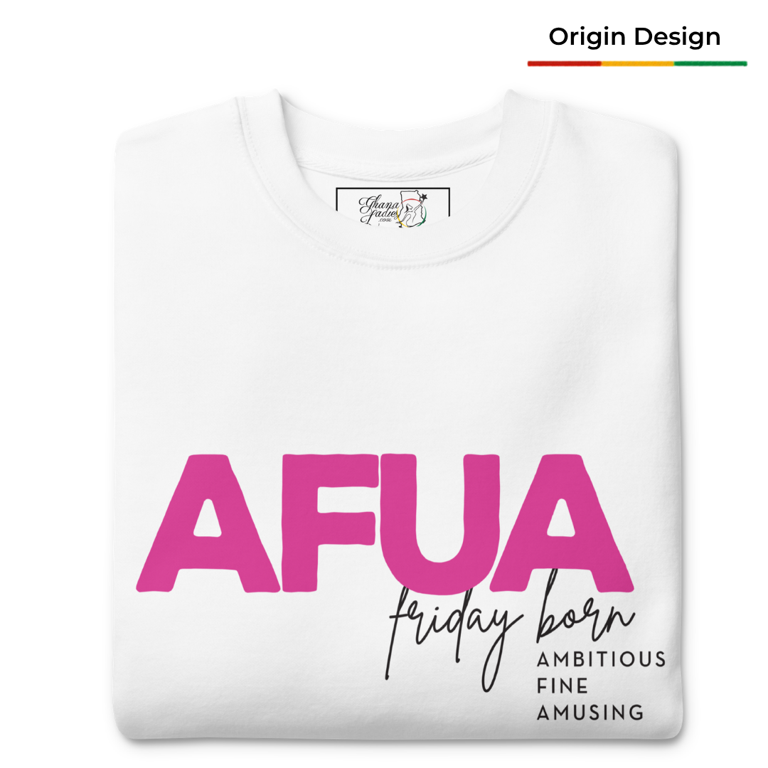 A folded white t-shirt with a graphic print reading 'AFUA' in bold pink letters, 'Friday born' in black script, and 'AMBITIOUS FINE AMUSING' in black block text. A small brand label is visible inside the collar, and an 'Origin Design' label is shown in the top right corner.