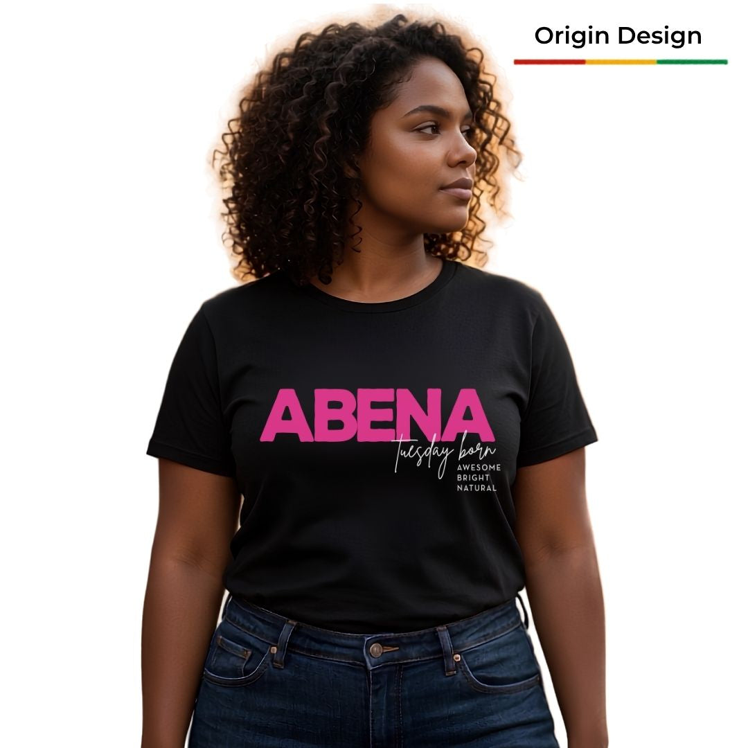 A woman wearing a black short-sleeve graphic T-shirt with the word 'ABENA' in bright pink and smaller white script text on the front, paired with dark blue jeans. The background is plain white.