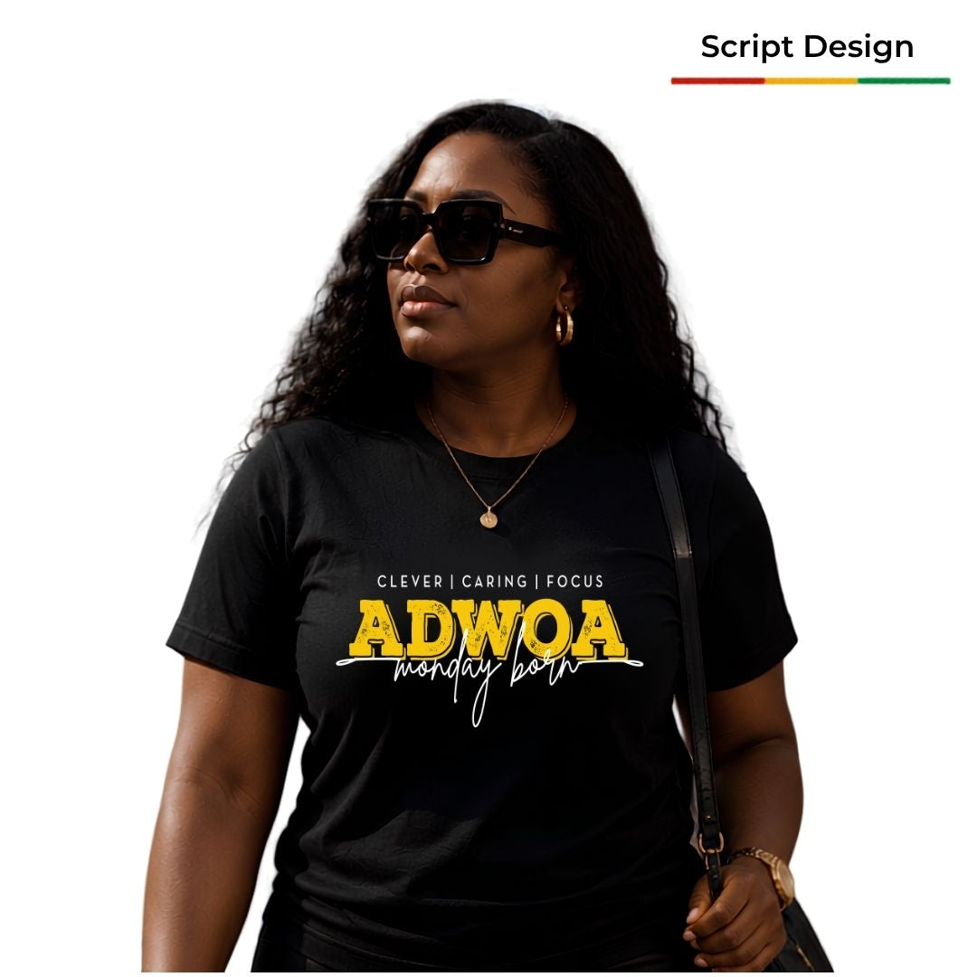 A woman wearing a black graphic t-shirt with yellow and white text that reads 'ADWOA monday born and 'CLEVER | CARING | FOCUS'. The image has a white background  and the model is holding a black shoulder bag.